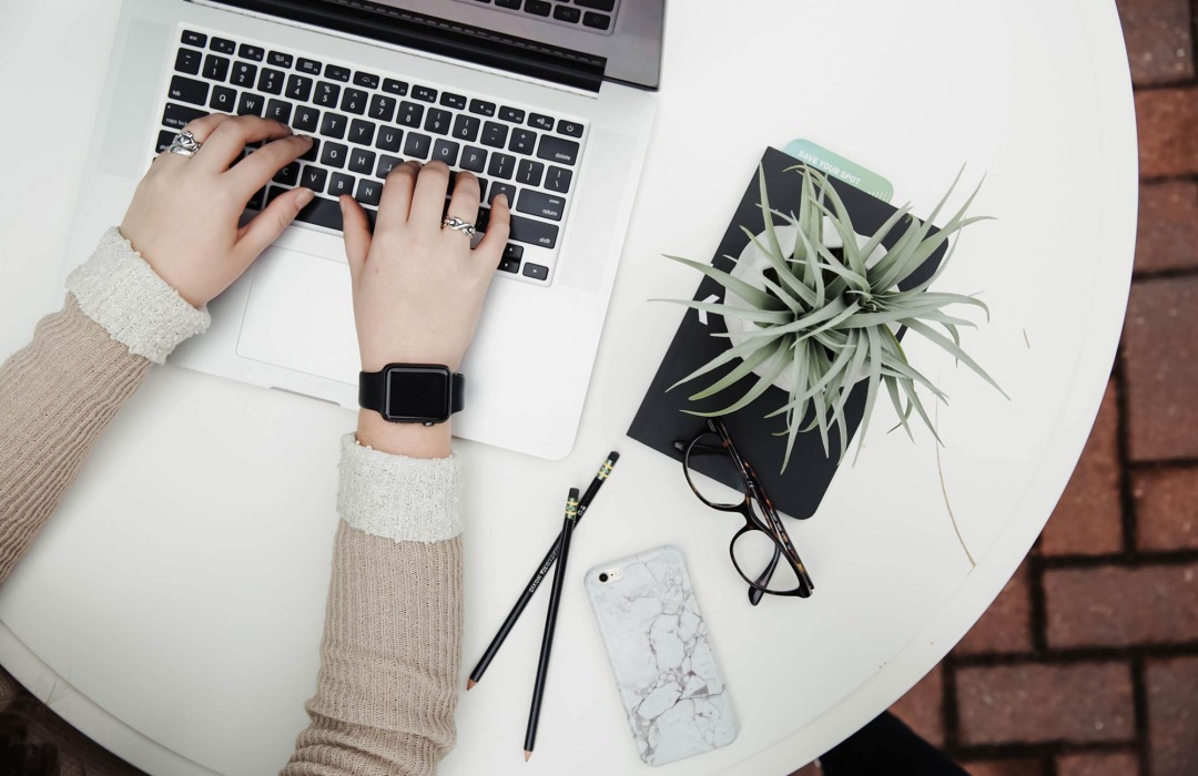 Asset Management Hands typing on a laptop beside some decor